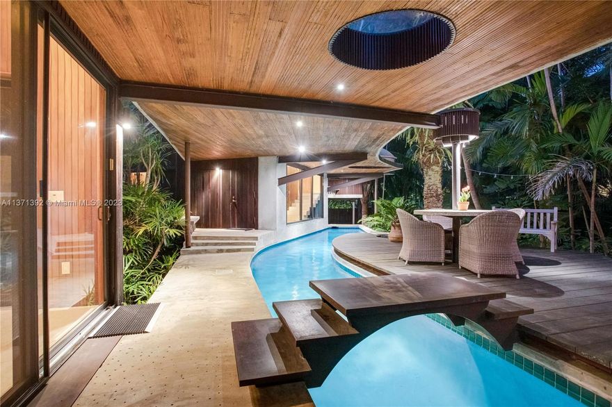 Built by iconic architect, Alfred Browning Parker, “Woodsong” is a rare tropical modern masterpiece in North Coconut Grove. Situated on elevated ground (Flood X Zone), this stunning home is surrounded by lush vegetation on an oversized lot. It is composed of three pods connected by an exterior breezeway lined by a lap pool, and is clad with solid mahogany that's reinforced by a steel frame and concrete base. Each structure has its own central A/C, tankless water heater, and floor-to-ceiling impact windows/skylights that allow for tons of natural light. The backyard includes a pool, sauna, and fresh-water pond. This artfully designed home is well maintained, and sits on a private street with walkability to parks, schools, the bay, and restaurants/bars in Miami's most desirable neighborhood.
