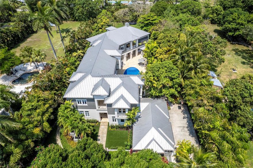 Enter through a private gate to find luxury at every turn. The grand living room boasts 28-foot ceilings and elegant pine floors throughout, and the gourmet kitchen impresses with a 12-foot island, 6-burner gas stove, Sub-Zero refrigerator, dual Wolf ovens, and a walk-in pantry. Set on a meticulously landscaped 1.3-acre  lot, the 9,000+ square foot estate features 6 beds, 6 baths, an office, and a 4-car garage; cypress ceilings, a Dominican coral deck, and a 30-foot outdoor gas fireplace create a magical ambiance. There are multiple terraces, 2 outdoor kitchens, 5 A/C units, 2 tankless water heaters, a metal roof, impact glass, a guest house, and maid quarters. A brilliant combination of impeccable craftsmanship, timeless architecture & incredible finishes.