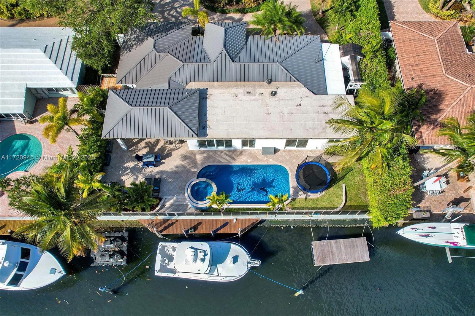 Welcome to your exclusive modern CORAL RIDGE WATERFRONT ESTATE with breathtaking water views, a true boater’s haven with a 100'seawall & 30ft dock. This architectural gem features impact windows & doors, sophisticated 4x4 porcelain flooring & seamless open-concept kitchen, Viking appliances, quartz countertops and elegant living space with LED lighting throughout, all overlooking the shimmering pool and canal. Master Suite with direct water view and exceptional large walk in closet. An entertainer's dream awaits with the expansive 24x12 covered patio, soaring ceilings, illuminated bar, sleek beverage cooler with lush & meticulously landscaping and 11 car parking, ensuring seamless hosting for any gathering. Steps from Galleria Mall, pristine beaches, fine dining, Bayview Elementary, parks.