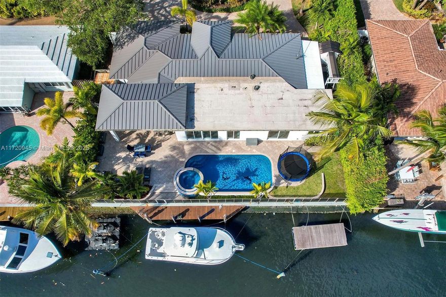 Welcome to your exclusive modern CORAL RIDGE WATERFRONT ESTATE with breathtaking water views, a true boater’s haven with a 100'seawall & 30ft dock. This architectural gem features impact windows & doors, sophisticated 4x4 porcelain flooring & seamless open-concept kitchen, Viking appliances, quartz countertops and elegant living space with LED lighting throughout, all overlooking the shimmering pool and canal. Master Suite with direct water view and exceptional large walk in closet. An entertainer's dream awaits with the expansive 24x12 covered patio, soaring ceilings, illuminated bar, sleek beverage cooler with lush & meticulously landscaping and 11 car parking, ensuring seamless hosting for any gathering. Steps from Galleria Mall, pristine beaches, fine dining, Bayview Elementary, parks.