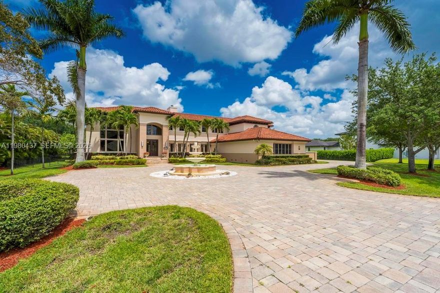 Tucked away in the exclusive enclave of Oak Hollow in Davie, this rare custom estate offers 5 bedrooms plus an office, complete hurricane impact windows/doors & roof replaced in 2017! Set on nearly a full acre this two-story residence invites you into a lifestyle defined by space, light, & timeless design. You’re greeted by a grand entrance with striking marble floors and soaring ceilings that immediately make a statement. Natural light pours into the formal living room, where a beautiful fireplace creates the perfect balance of warmth and sophistication. Formal dining room sets the stage for memorable gatherings, seamlessly connecting elegance with everyday living. At the heart of the home, the gourmet kitchen is designed to impress, featuring rich wood cabinetry, granite countertops, and top-of-the-line appliances, all flowing effortlessly into the main living areas perfect for both intimate moments and entertaining on a larger scale. The first floor offers a private guest suite with its own bathroom, ideal for visitors or extended family. Upstairs, real wood floors lead you to the remaining bedrooms, each thoughtfully designed with its own bath, while the primary suite offers a true retreat complete with spacious walk-in closets with custom cabinetry, blending function with refined design. A resort-style pool and spa are surrounded by expansive outdoor living spaces, offering the perfect setting to unwind, entertain, and enjoy the serenity of your own private retreat.