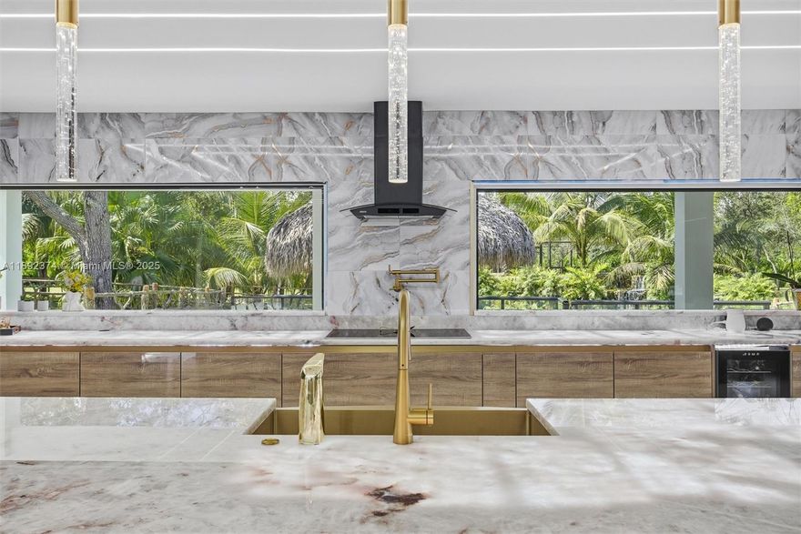 Resort living on five lush acres. This turnkey Redland estate offers a renovated 4,000 sf showpiece framed by waterfalls and two ponds. Blue metal roof with solar, impact windows/doors, wide covered terrace, and a grand motor court. Chef's kitchen with illuminated stone, oversized island, custom cabinetry, premium appliances, and wine and beverage towers. Sleek LED ceilings, a dramatic stone fireplace, and walls of glass. Two primary suites with spa baths and polished porcelain bathrooms, plus an upstairs balcony. Entertain with an outdoor kitchen and large tiki by the natural lagoon. A new four-bay steel workshop and separate covered parking fit RVs, boats, and collections. Endless possibilities. Minutes to US 1 and Redland markets.