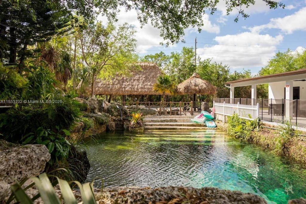 Discover your own slice of paradise in the Redland on 4.5 acres with a lush private forest, resort-style pool grotto with cascading waterfall, and natural spring aquifer. Perfectly located between Biscayne & Everglades National Parks, just 10 miles from Tamiami Executive Airport and 30 miles from Miami International Airport & Key Largo. This split-plan home offers impact windows, a remodeled kitchen with stainless steel appliances, and a serene master suite with spa tub and shower. French doors open to a terrace with stunning grotto and forest views, ideal for relaxing, entertaining, and dining. Includes tiki hut, self-sustaining water source, and agricultural zoning. Subject to NFC & EEL covenants.All info deemed accurate but must be independently verified. Call LA to schedule showings.