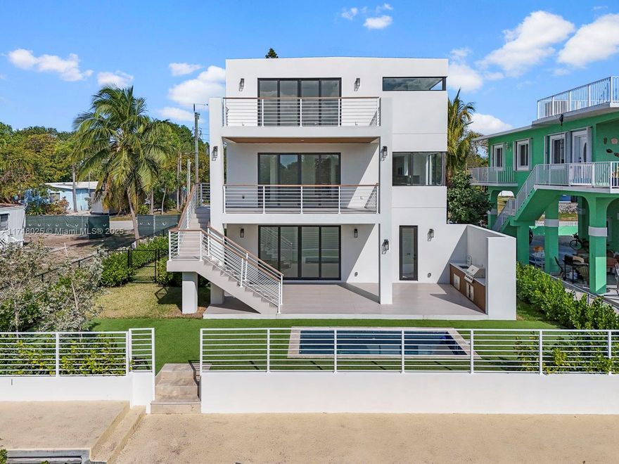 This brand-new tri-level home in the FL Keys perfectly captures the essence of sophisticated luxury & relaxed island living. With both bay & ocean access, 60 ft. of canal frontage + private concrete dock, it's ideal for saltwater enthusiasts. The home flows seamlessly from the rec room & summer kitchen to pool area, all set in a fenced yard - perfect for kids & pets. The 2nd level offers open living & dining, kitchen island, sleek wet bar & laundry room. An expansive balcony is perfect for family dinners & unwinding. Upstairs, elegant finishes & water views offer a peaceful master retreat. Just blocks from Tavernier Marina & fuel station, close to the top dining spots in Islamorada & only 90 mins. from Miami, this home is an ideal vacation retreat w/no HOA & great rental income potential.