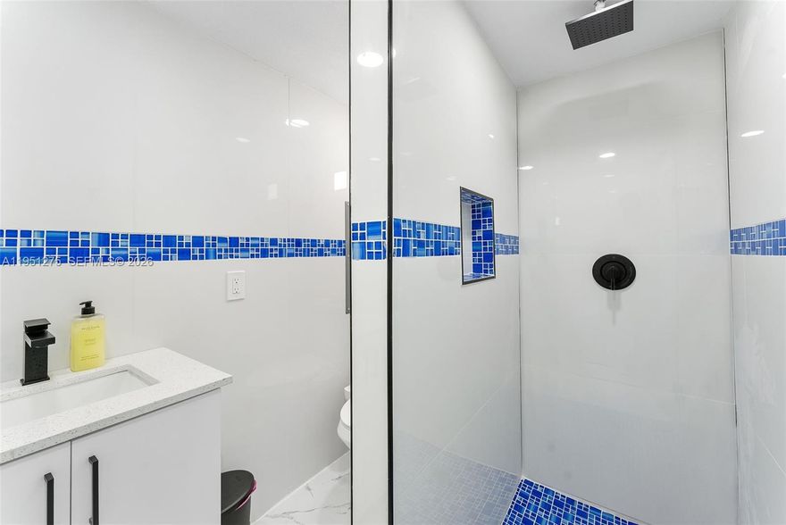 This beautifully updated pool home features sleek white porcelain tile flooring throughout and soaring high ceilings. The centerpiece of the home is a glass-enclosed wine cellar, ideal for showcasing your collection as well as the kitchen which ties up the space perfectly with extra high cabinets and island great for entertaining. High-impact windows and doors throughout the home create a space with lots of sunlight to enter the home. Outside, enjoy a the heated pool on a cool deck surrounded with high quality pavers, an outdoor kitchen area for gatherings, and a cabana bath for convenience. Plus, with double-wide gated side access on both sides, there’s ample space for your RV or boat. This is the ultimate blend of style, function, and outdoor living!