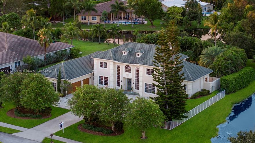 Back On The Market! Now Is your Opportunity to Own a Captivating, Unique Estate- nestled in Saddle Club Estates on a sprawling, .75 Acre lot. Bathed in natural light, this residence boasts south/north sun exposure. The gourmet kitchen features top-of-the-line appliances, custom cabinetry, and a generous island. The Primary suite located on the ground floor accompanies a spa-like en-suite bath and his & hers closets. A first-floor in-law suite includes an en-suite cabana bath. Enjoy water, garden, and pool views throughout the home. Highlights include impact windows, saltwater heated pool, grand upstairs loft,& custom cabinetry in the 3+ car garage. Revel in unparalleled privacy, free from direct neighbors across the street or on both sides.