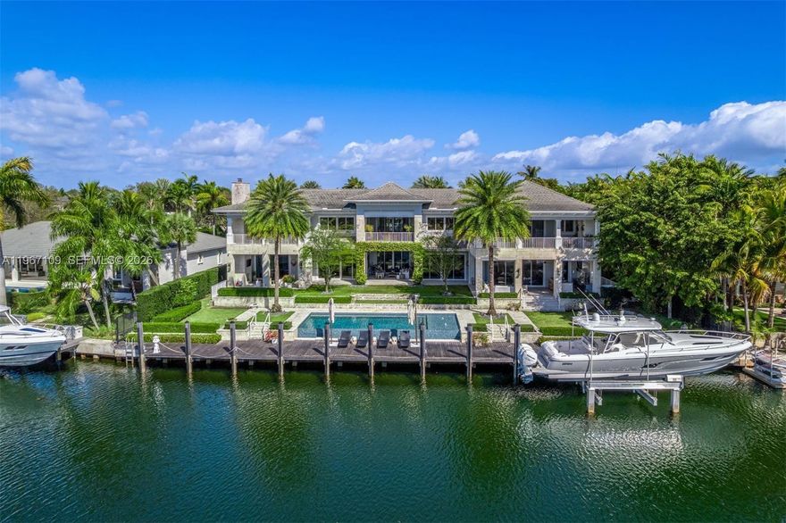 Elegant Coastal Mediterranean-inspired waterfront estate within the exclusive, guard-gated enclave of Old Cutler Bay in Coral Gables. Set on a 20,300 SF lot with 140 ft on a wide canal and direct, bridge-free access to Biscayne Bay, this 11,589 total SF, 6-bedroom, 7-full and 2-half bath residence is designed to feel open, airy, and truly expansive. Multiple oversized covered terraces and upper-level balconies span the façade, creating various outdoor living and dining areas ideal for grand-scale entertaining or intimate gatherings. Framed by manicured grounds, coral stone accents, and a gracious entry with koi pond, the home seamlessly blurs the line between indoors and out. The resort-caliber exterior showcases an infinity-edge saltwater pool with Baja ledge and fountain bubblers, a coral stone deck, and a fully equipped summer kitchen. An 80-foot private dock further enhances the waterfront lifestyle. Inside, a dramatic entry with soaring vertical scale and exposed beams introduces light-filled interiors finished with limestone and wood floors, custom millwork, illuminated wine cellar, elevator, and integrated smart home technology. The bespoke chef’s kitchen features custom cabinetry, a striking Blue Agate island, and premium Wolf and Sub-Zero appliances. The tranquil primary suite offers vaulted shiplap ceilings, private canal-view terraces, a spa-inspired marble bath, and couture-style dressing room—an exceptional blend of scale, comfort, and timeless waterfront luxury.