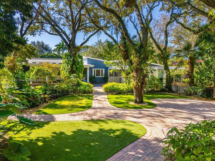 Welcome to Paradise! This stunningly beautiful entertainer's home in the Estate section of South Miami sits on a luxuriant tropical builder's acre with exotic landscape, a swimming pool, and a waterfall pond. Once featured in the Villagers Garden Tour, the remarkable home consists of 3 structures: The main has 3 bedroom suites + 2 dens, 4 bathrooms, a living room w/fireplace, open family and dining rooms, a media - playroom, and a gourmet kitchen w/ gas & electric stoves. Pass through a patio breezeway to access a Full Guest Qtrs. complete with full kitchen, 2 addl. bedrooms, 1 bath.  A detached pool house w/bathrm is great for a live-in nanny suite. The home has peaceful views and many attributes; impact windows + doors, solar panels, a summer kitchen, a hobby shed, and ever so much more.