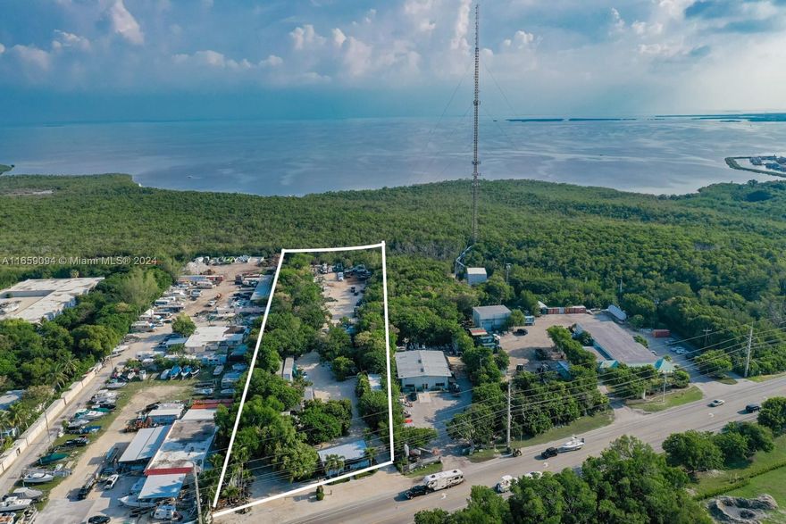 This property features 3 acres of industrial upland, complemented by an additional 9 acres of bayfront land, which can be negotiated, including plans for a 100' dock and two 30k lb boat lifts. The property has 150 ft of US1 frontage and is conveniently located north of the weigh station. The Village of Islamorada officially recognizes 1,972 sq. ft. of non-residential floor area, one market-rate dwelling unit, and two affordable housing units. The current zoning code permits the construction of over 30,000 square feet, based on 3.12 acres or 10,000 sq. ft. per acre. Presently, there are four structures on the property. The seller is open to subdividing to meet the buyer's needs. This is one of the few properties in Monroe County with a wide range of potential uses, including residential.