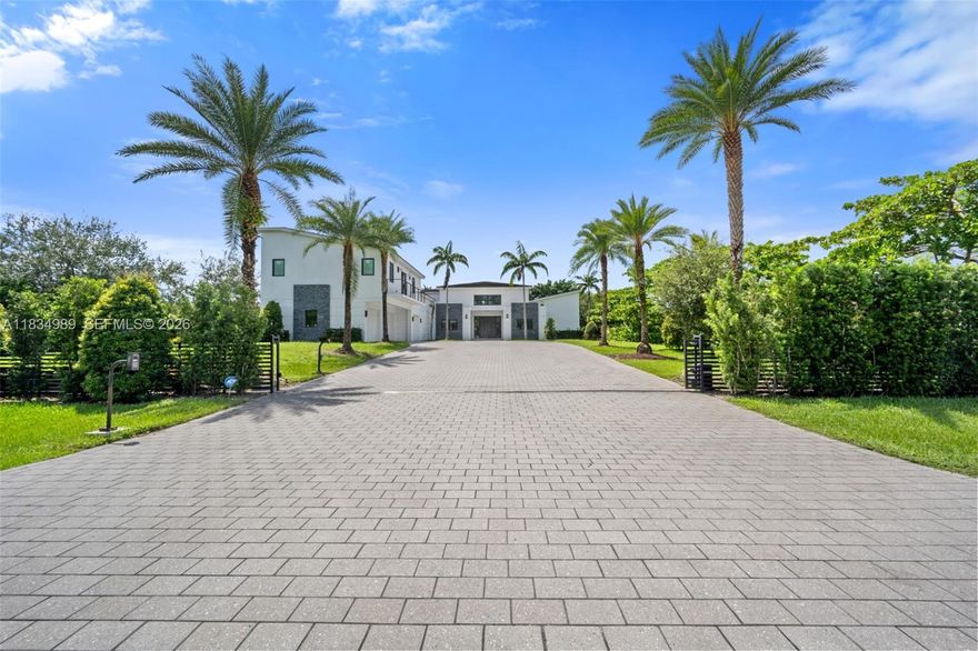 Modern masterpiece on expansive grounds, boasting soaring 20-ft ceilings, sleek porcelain floors, and a chef’s kitchen with custom cabinetry and quartz counters. Six spacious bedrooms each offer private ensuite baths and custom walk-in closets. The lavish primary suite features a serene sitting area, dual walk-in closets (his and hers), and a luxe glam room with built-ins for shoes, handbags, and makeup. A private elevator provides access to the second level, where you’ll find a stunning home theater, bar, and kitchen. Outdoors, indulge in resort-style living with a saltwater pool, spa, summer kitchen, covered terrace, and an impressive driveway with a 3-car garage. Smart, energy-efficient, and built for ultimate contemporary living.