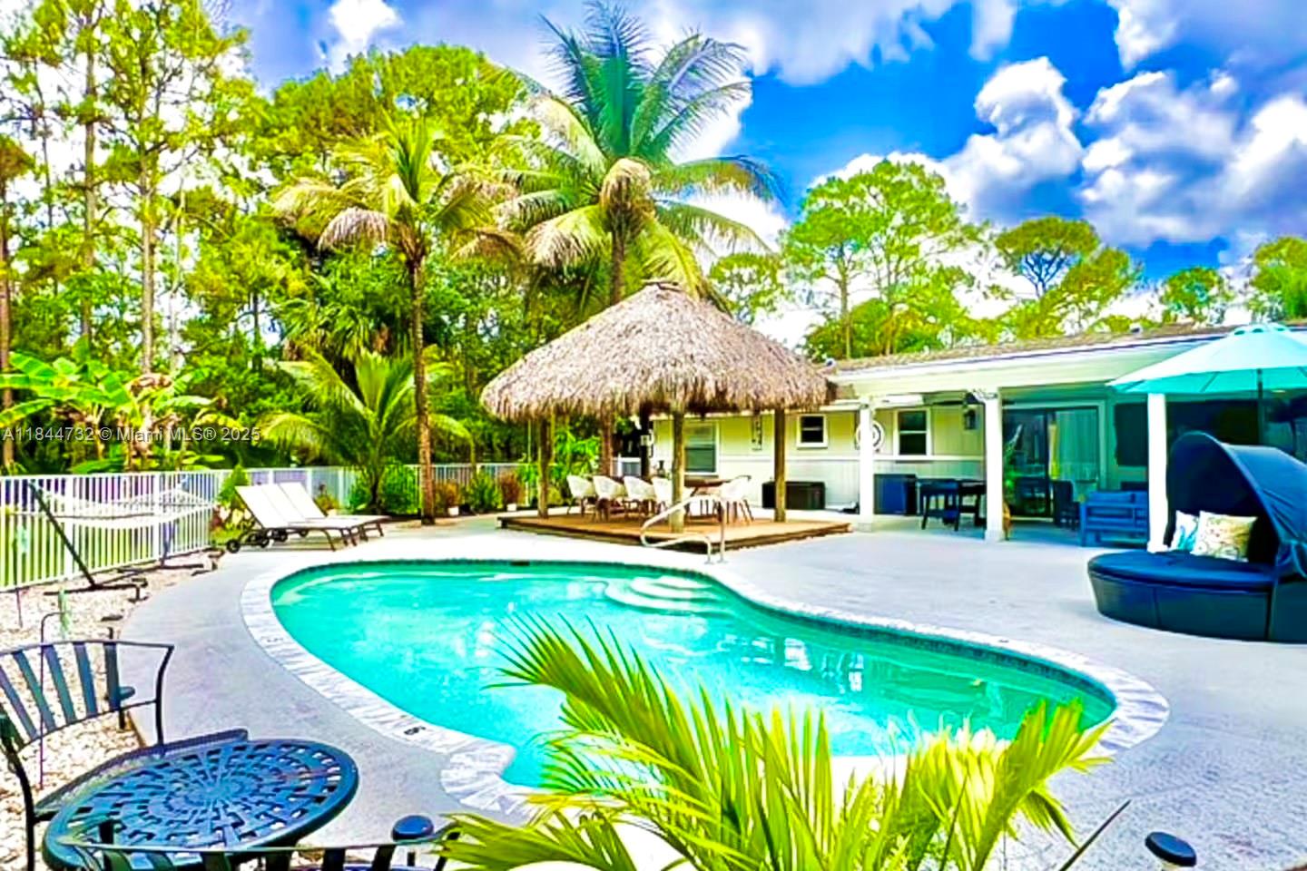 Welcome to Villa Las Palmas — the kind of place that makes you want to take off your shoes, pour a drink, and never leave. Nestled on 1.16 acres of lush, tropical land, this 4-bedroom, 2-bath home has been completely transformed into a bright, modern escape. Step inside and you’ll immediately notice the fresh paint, the rich new flooring underfoot, and a kitchen that looks like it belongs in a design magazine — brand-new appliances, crisp white cabinetry, and waterfall countertops that are as durable as they are stunning. But where this home really shines is outside. Whether you're floating in the sparkling pool, lounging under the brand-new custom gazebo, or picking bananas from your own trees, you’ll feel like you’re on a permanent vacation. This is not just a home it's a lifestyle.