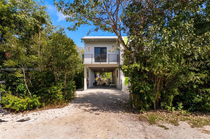 Step into a fresh take on coastal living in this newly built Key Largo home, where contemporary design meets the relaxed charm of the Florida Keys. Elevated in traditional stilt fashion, the residence is constructed for both beauty and strength, featuring a solid concrete roof and impact-rated windows and doors that provide durability and peace of mind. The interior offers a spacious and welcoming atmosphere with five bedrooms, eight-foot ceilings, and large-format tile flooring that enhances the home's clean, modern aesthetic. The open-concept layout creates an effortless flow throughout the main living spaces, ideal for both everyday living and hosting guests. A separate lower-level living area adds valuable versatility, complete with two bedrooms and a full bathroom, providing a comfortable space for guests, extended family, or additional private accommodations. Upstairs, the main living area opens onto a generous outdoor patio, where you can enjoy gentle island breezes and the beauty of the surrounding tropical environment. The well-appointed kitchen is both stylish and functional, featuring ample counter space, sleek modern finishes, and a large statement sink that stands out as a unique design feature. Designed with entertaining in mind, the outdoor space includes a ground-level BBQ kitchen set on pavers, creating the perfect setting for gatherings after a day of boating, fishing, or exploring the Keys.