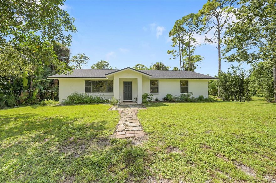 Beautifully updated 3BR/2BA home on 1.48 acres in The Acreage! Features include a new roof on all structures, fresh interior/exterior paint, new front fencing, updated fixtures & lighting, newer appliances (2023), washer/dryer (2021), new water pump & private fence for water system. Property is bordered by 2 canals for privacy and boasts fruit trees (mango, avocado, pineapple, papaya) plus a majestic banyan tree with swing. Large utility room offers extra storage. No HOA—move-in ready! With its combination of character, recent improvements, and a serene natural setting, this property is truly one of a kind.