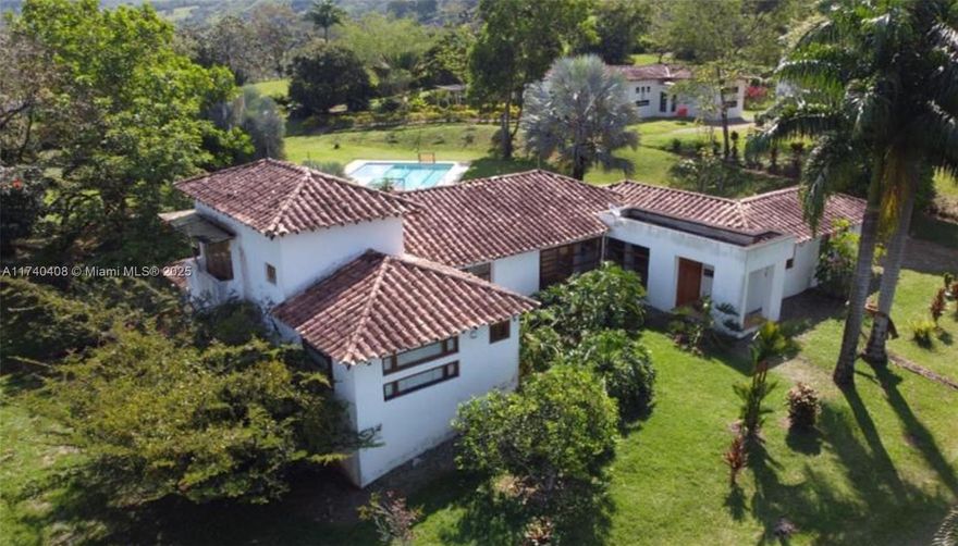 Embrace the idyllic rural  country living in this picturesque estate located in Antioquia, Colombia. Just a 1.5 hour drive from Medellin, this property consists of 2 separate houses, a 2-story caretaker house and a pool. Upscale gated community with 24 hour security guard and a total of 65 lots. House #1 is a tri-level home with 5 bedrooms/3bathrooms, impressive high vaulted ceilings with exposed wood beams, maid's quarters, large open kitchen, formal living and dining, laundry room and custom built-ins. Beautiful brick flooring throughout the home, covered outdoor terraces and large wood casement windows. House #2 is a 4 bedroom/4 bathroom with exact finishes as house #1. Separate guest house with 2 bedrooms/1bath upstairs and two garage spaces on ground floor. Furniture included, low HOA