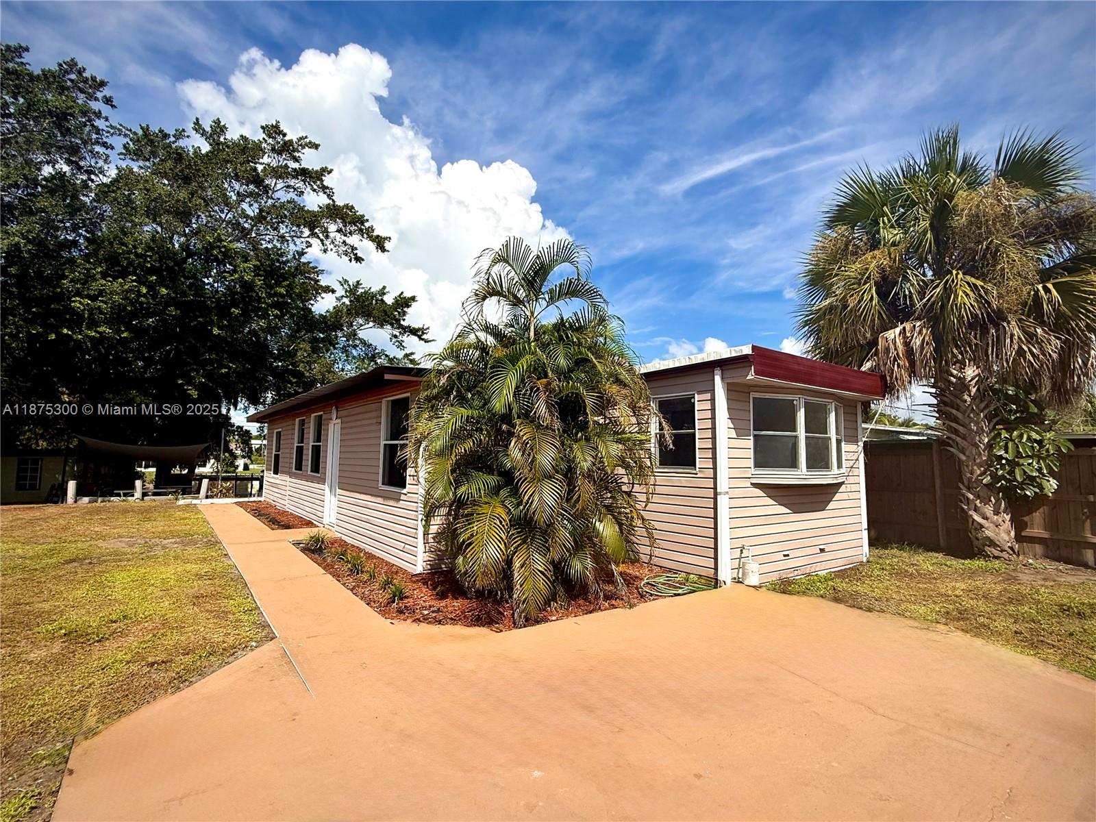 Lake Okeechobee canal-front property in Treasure Island—surveyed lot with space for boats, trailers, or toys. Renovated 3BD/2BA mobile home with addition. Updates include kitchen, flooring, windows, split A/C units, privacy fencing with reinforced gates, exterior lighting, large shed, extended concrete driveway, and multiple water spigots. Shaded outdoor area with concrete pad under Grandfather oak—ideal for gatherings. Avocado tree and mature landscaping. City water, septic, no flood zone, no HOA. Quiet street with easy access to coastal cities. Easy to show!
