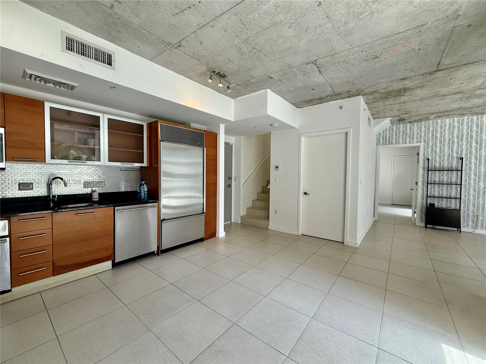 Spacious two-story penthouse in the heart of Midtown Miami featuring 2 bedrooms, 2.5 bathrooms, and a versatile den ideal for a home office or media room. This light-filled residence boasts floor-to-ceiling windows, exposed concrete ceilings, and three private balconies overlooking the serene pool area. The second floor showcases soaring 12-foot ceilings, enhancing the open, loft-style feel. While the interior remains in well-maintained original condition, it offers a fantastic canvas for customization. Includes one assigned covered parking space, ample closet space, and a smartly designed floor plan. Located in the sought-after 2 Midtown building with top-tier amenities including a resort-style pool, large fitness center, and 24-hour security.