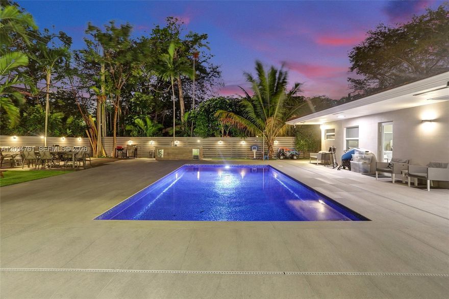 Welcome to this beautifully maintained modern one story home in the sought after Skylake neighborhood of North Miami Beach. Located on a semi private street and set on a lot of up to 13000 sq ft, this property offers privacy, comfort, and style. The home features 5 bedrooms and 3 bathrooms, including a spacious primary suite with a sitting area, dual sinks, and a sleek shower. A split bedroom layout provides flexibility and privacy. The layout includes a formal dining area, a family and dining combination, and a counter that connects the kitchen and living areas. The kitchen features a Taj Mahal marble countertop and essential appliances including a wall oven, electric range, microwave, dishwasher, and disposal. Porcelain flooring runs throughout, and impact windows provide security and efficiency. The home also includes a security camera system. Enjoy the backyard with a mosaic tiled pool featuring a saltwater system and heater, open porch, outdoor kitchen, artificial turf, and plenty of space for entertaining. Additional features include a 2 car garage, driveway parking, laundry area, and central air and heating. Do not miss this opportunity in North Miami Beach.