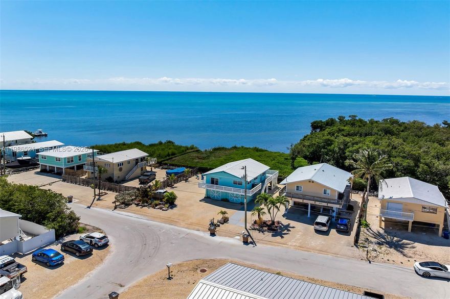 Welcome to your slice of paradise in Marathon, where island living meets exceptional investment potential. Tucked at the end of a quiet street in mid-town, this upgraded property captures sweeping Atlantic Ocean views and boasts a strong short-term rental history - ideal as both a private retreat and income-producing asset. Expansive parking accommodates boats, multiple vehicles, RVs, and even an EV charging station, a rare find in the Keys. Lush landscaping with palms, raised garden beds, and automated irrigation creates a true tropical oasis with effortless upkeep. Inside, the updated kitchen features new appliances (2021), a stylish island, refreshed countertops and backsplash, and a functional pantry, perfect for entertaining. Thoughtful upgrades include Spanish tile work, blackout shades, updated ceiling fans, and refinished custom woodwork. Enjoy ocean views from the primary suite’s walk-in shower or unwind in the jetted whirlpool tub. Designed for both durability and efficiency, the home includes hurricane-impact windows and doors, upgraded insulation, a new central air system (2021) with A/C compressor (2026), refurbished roof (2021), a dryer duct fan, and numerous system upgrades. Outdoor living shines with a wraparound porch, outdoor shower, privacy wall, and garden shed. Whether you're seeking a full-time residence, vacation escape, or high-performing rental, this Marathon gem delivers on lifestyle, function, and location.