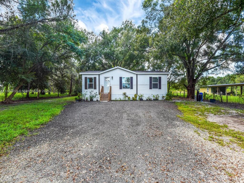 Located just outside the heart of LaBelle, this newly built 2024 manufactured home offers 3 bedrooms and 2 bathrooms on a spacious one-acre lot. The interior is bright and inviting with modern laminate floors and an open kitchen featuring bar seating and contemporary cabinetry. Step outside to enjoy peaceful evenings on the patio overlooking mature trees and a private, wooded backdrop. The property is dotted with fruit trees and provides plenty of room for outdoor activities, gardening, or simply relaxing in the quiet setting. With simple, low-maintenance landscaping and a perfect blend of modern design and rural charm, this home is an ideal retreat for anyone seeking the comfort of new construction in a tranquil country atmosphere.