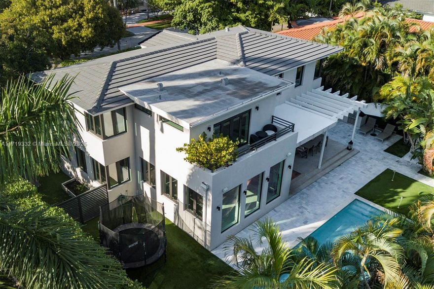 A true architectural masterpiece, this reimagined mid-century modern Miami Beach home exudes timeless elegance. Completed in 2020, this 6-bed, 5.5-bath sanctuary is bathed in natural light w/ an open floor plan, expansive rooms, & walls of windows. Floor-to-ceiling glass & pocket doors in the kitchen seamlessly connect the indoors to the lush outdoor living area. The home sits on a manicured 11,116 SF corner lot with Italian finishes, wide white oak floors, & a CESAR kitchen w/ DACOR & MIELE appliances. Outdoors, enjoy a heated saltwater pool, gourmet chef’s kitchen, putting green, adult-sized chessboard, trampoline, & premium Astroturf. Ambient lighting & mature landscaping create a serene private retreat. A sleek custom 2-car carport & private 1-bedroom guesthouse complete this treasure.