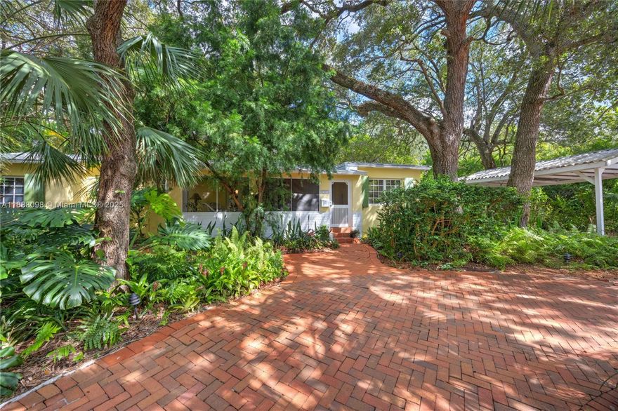 Open kitchen, dining room, split bedrooms, metal roof, circular brick drive, large back patio and carport on a quarter acre with magnificent trees and landscaping. The whimsical kitchen includes: antique leaded glass cabinets, open shelving, honed granite counters, a deep enamel sink in custom cabinet. Impeccably maintained, classic Florida vernacular design: elevated foundation, expansive windows, deep overhangs, screened porch. Metal Roof 2014; AC 2025; Drainfield 2017; newer appliances (2023), Hardwood Floors, gas range, outdoor shower, Nest thermostat and smoke detector, Landscape lighting, Native Plan Network certified yard. Located in the vibrant Biltmore Heights neighborhood on a quiet non-through street. Minutes to downtown South Miami and Coral Gables. Walking distance to UM. Wow!