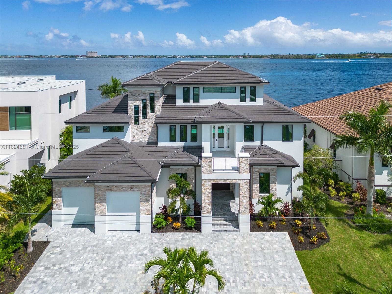Stunning new construction ultra-luxury waterfront estate in Cape Coral w/10,463 adj. sqft and 80ft of waterfrontage. Inside, a grand living room with soaring vaulted ceilings & expansive floor-to-ceiling windows showcases panoramic views of the Caloosahatchee River. The open layout flows into a gourmet kitchen with imported Italian cabinetry & top-tier appliances. The primary suite includes a private balcony with breathtaking water views & spa-style bath with sauna. The 3rd floor features a multipurpose family room, large terrace & home theater setup. Additional features: private elevator, safe room & smart home tech. Outside, enjoy an infinity-edge pool, a wooden dock & tiki bar, perfect for entertaining. Thoughtfully designed to elevate every aspect of luxury waterfront living.