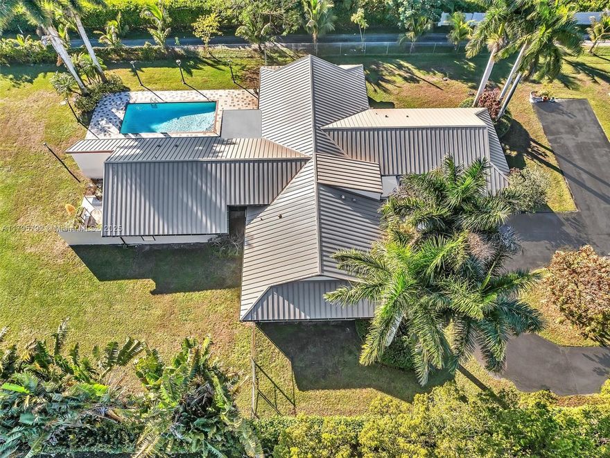 Offered below appraisal! Great value! Drive through the gates. Follow the tree-lined driveway to this custom estate nestled on over 2 acres, set on one of the most coveted streets in Southwest Ranches. This home invites you in with its distinctive yet casual design and attention to detail. Fruit-bearing trees and lush foliage create a backdrop for creating memories. 5 beds/3.5 baths + 28x18 flex room, ideal for media, gym or recreational space. Vaulted ceilings w/wood finishes add a unique touch and multitude of glass sliders frame the picturesque outdoor views. Step outside to the spacious L-shaped covered patio and relax or entertain beside the oversized heated pool. Standing seam metal roof and gutters 2023, whole house generator, hurricane screens. 3 ACs, extra deep 2 car garage.