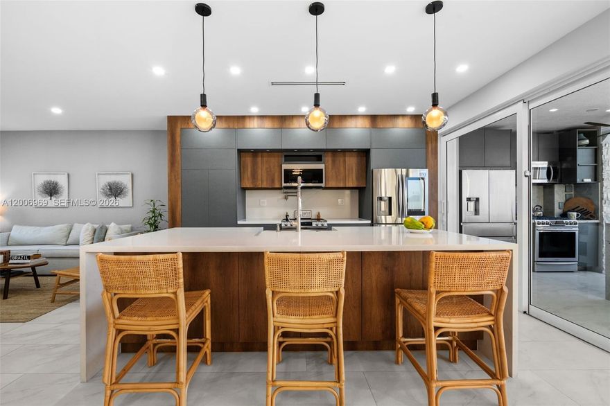 This completely reimagined lakefront residence has been fully remodeled in 2023, 5 bedrooms 4 and 1/2 bathrooms with over 2,900 sqft2 of AC living area. Offering the feel of a brand-new home with every major component redone, from plumbing and electrical to the roof, pool, and interior finishes. The clean, modern design creates a bright, open layout with thoughtfully finished interiors. Upon entry, a striking floating metal and wood staircase sets the tone, perfectly framed by stunning water views. The kitchen was designed for both daily living and entertaining, featuring smart appliances, a wine bar, and sleek cabinetry with ample storage. The main living areas open up through impressive 20-foot floor-to-ceiling sliding glass doors, creating a natural transition to the outdoor space while bringing in constant light and unobstructed lake views. The primary suite is spacious and private, with a large bathroom designed with a spa-like feel and a custom boutique-style closet. Additional features: EV charger, owned solar, gas summer kitchen, tankless water heater, 200-amp underground service, Cat-5 wiring, and expanded paver driveway. Sophistication, smart tech, and resort-style living in Weston's premier