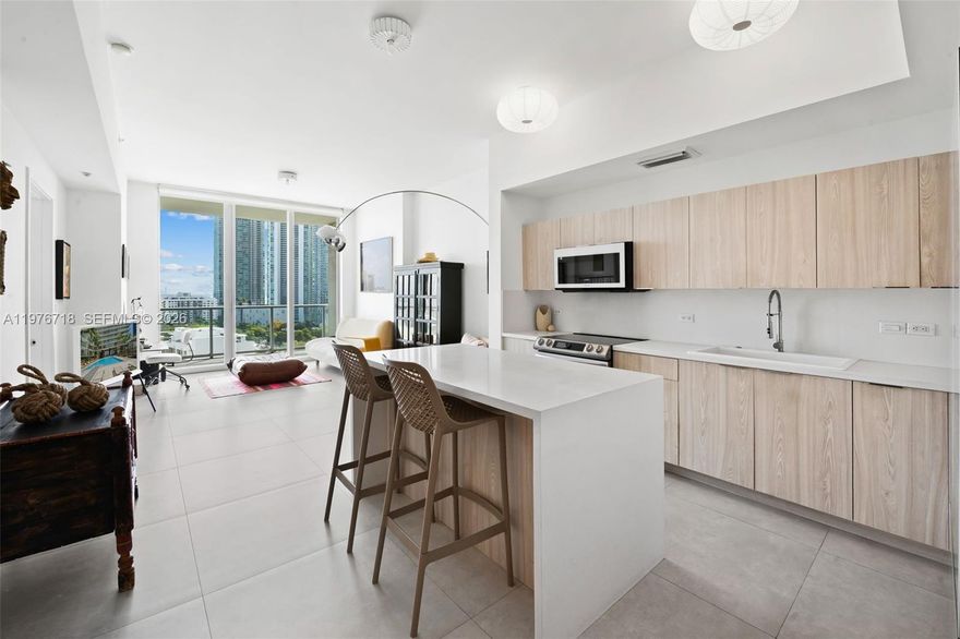 This is the kind of home that arrives completely renovated, thoughtfully considered, and positioned in one of Midtown Miami's most desirable buildings with views of Biscayne Bay and the skyline framed by a large balcony with glass railings that feels like an extension of the living space.

The residence itself is oversized for the category a true one-bedroom with soaring ceilings, a proper guest bath, and a layout that breathes. The renovation is tasteful: light-wood cabinetry, white stone countertops, and stainless steel appliances anchor a kitchen that reads clean without trying too hard. Large-format tile flows throughout, keeping the home bright and effortless to maintain. An in-unit washer/dryer adds the kind of quiet practicality that elevates daily life.

The primary bath has been fully reimagined matte black fixtures, rain shower head, refined vanity and lighting achieving that boutique-hotel quality that defines Midtown’s better renovations. The guest bath allows the home to function equally well for a couple, a pied-à-terre buyer, or an investor seeking a strong rental profile in one of the city's highest-demand corridors.

At 2Midtown, the amenity program is resort-caliber: bay-view fitness center, resort pool, hot tub, sauna, steam, dipping pools, concierge service, and covered parking with EV chargers. Midtown's everyday retail, the Design District's luxury flagship ecosystem, Wynwood's cultural energy, and the beach via the Julia Tuttle all within minutes.