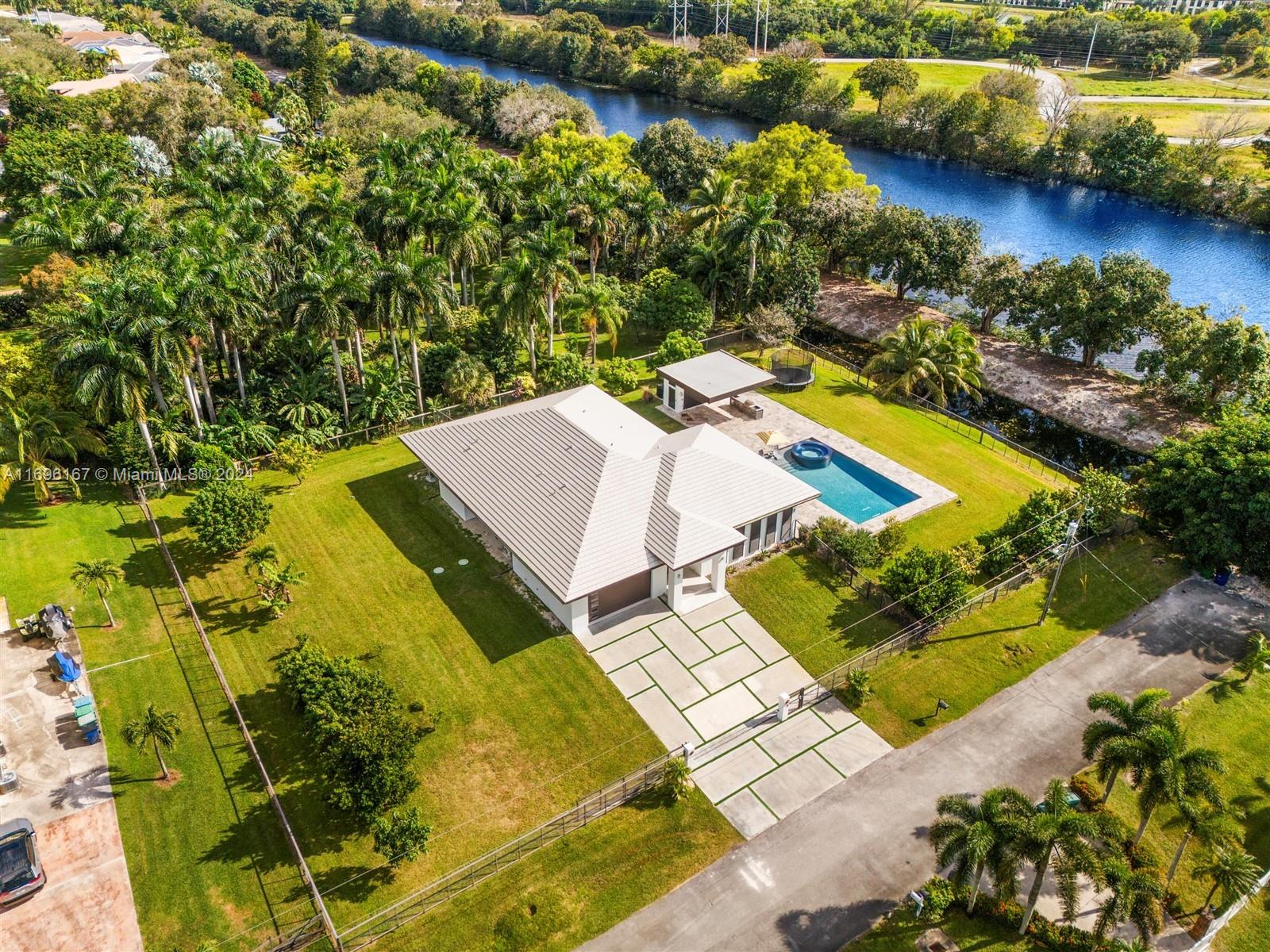 This stunning 4b/4.5bath 2019-built luxury private home in Cooper City is a fortress of resilience and elegance, designed to withstand 200+ mph hurricane winds. Built on the dead end street surrounded by nature. Built with reinforced concrete walls, high-impact windows, and a hurricane-proof roof. Set on a private 1 acre lot with exclusive canal and lake access. The property features a heated 25x40 ft pool, 10-ft jacuzzi, and a sleek modern cantilever outdoor cabana with a full kitchen, sound system, fruit trees, and TV for year-round entertainment. Perfect for GRAND PARTIES! Enjoy unparalleled privacy, energy efficiency, and eco-friendly design, all within walking distance to top A rated schools. No HOA fees, this home offers the perfect blend of security, luxury, nature, and convenience.