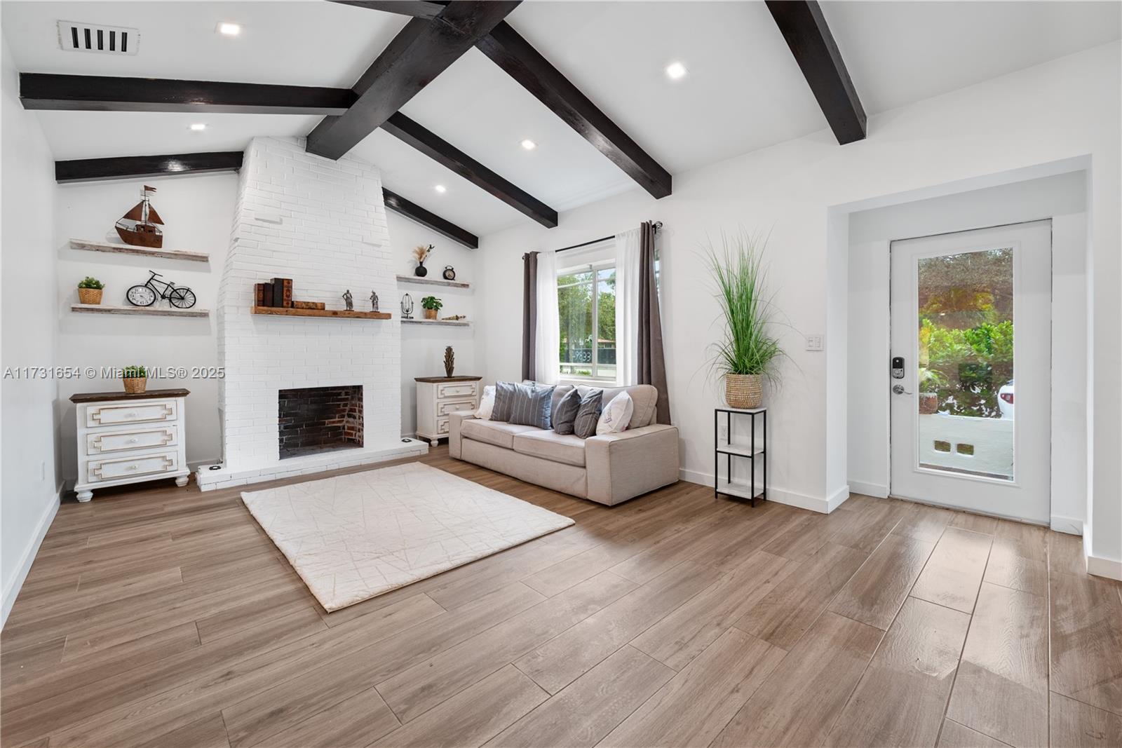 Discover modern elegance in this 3-bedroom, 2.5-bath Miami Shores home. The living room features vaulted ceilings, exposed wooden beams, a white brick fireplace, and abundant natural light. The open-concept kitchen shines with dark cabinetry, a butcher-block countertop, stainless steel appliances, and a custom wine display. Spacious bedrooms include custom closets, and the bathrooms offer stylish finishes and functionality. With a seamless blend of charm and sophistication, this home is perfect for both relaxing and entertaining in a prime location. Available furnished!