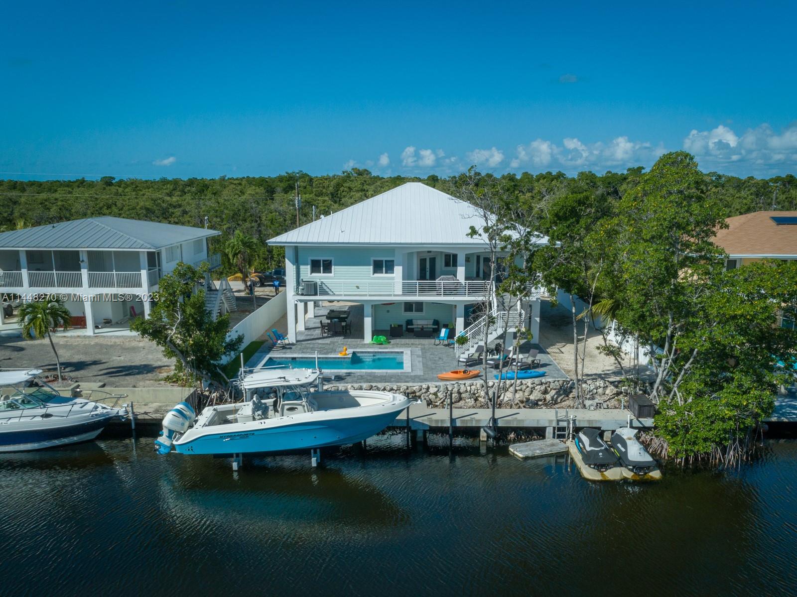 Modern Contemporary Pool Home : Where Every Day Transforms into a Vacation. Step into this beauty, fully-equipped turnkey home that offersall the essentials for relishing in paradise. Envision delightful gatherings with friends and family by the pool, while taking in the serene vista of the dock and expansive backyard. This exquisite residence, freshly constructed in 2015, boasts 3 bedrooms and 2 baths. Its open-concept design, adorned with lofty ceilings, is meticulously appointed, and comes tastefully furnished. A 75-foot dock, accompanied by a 15,000-pound boat lift, grants swift and effortless access to open waters, mere minutes away from waterfront activities and fine dining.