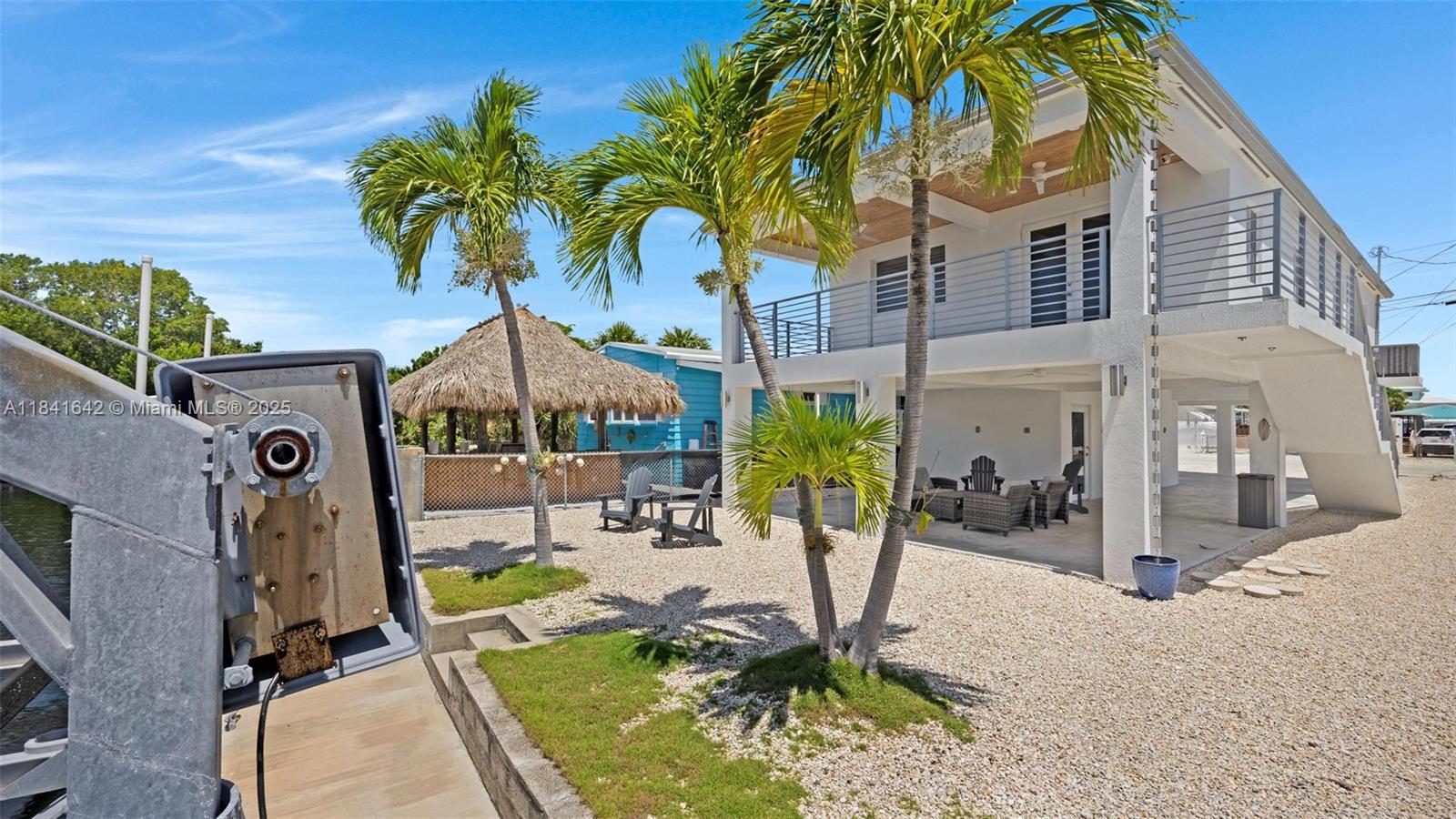 Experience waterfront luxury in this turnkey, CBS-built coastal retreat on Key Largo's bayside. Constructed in 2020 and thoughtfully renovated in 2021, this 3-bedroom, 2-bath residence sits on a generous ~4,000?sf lot. The chef’s kitchen features high-end Viking & LG appliances—including a 36? gas range, wine cooler, microwave drawer, pot filler—and quartzite countertops. The seamless open layout flows through to a covered porch perfect for entertaining. Outside, enjoy a 40' concrete dock with a 5,500-lb davit, new 15,000-lb lift, plus 299?sf of storage. Luxury finishes include 9' ceilings, 8' exterior & 7' interior doors, metal roof, tile floors, impact windows/doors, central AC, ceiling fans, and a 4-space carport with trailer storage. This home offers unmatched island living.