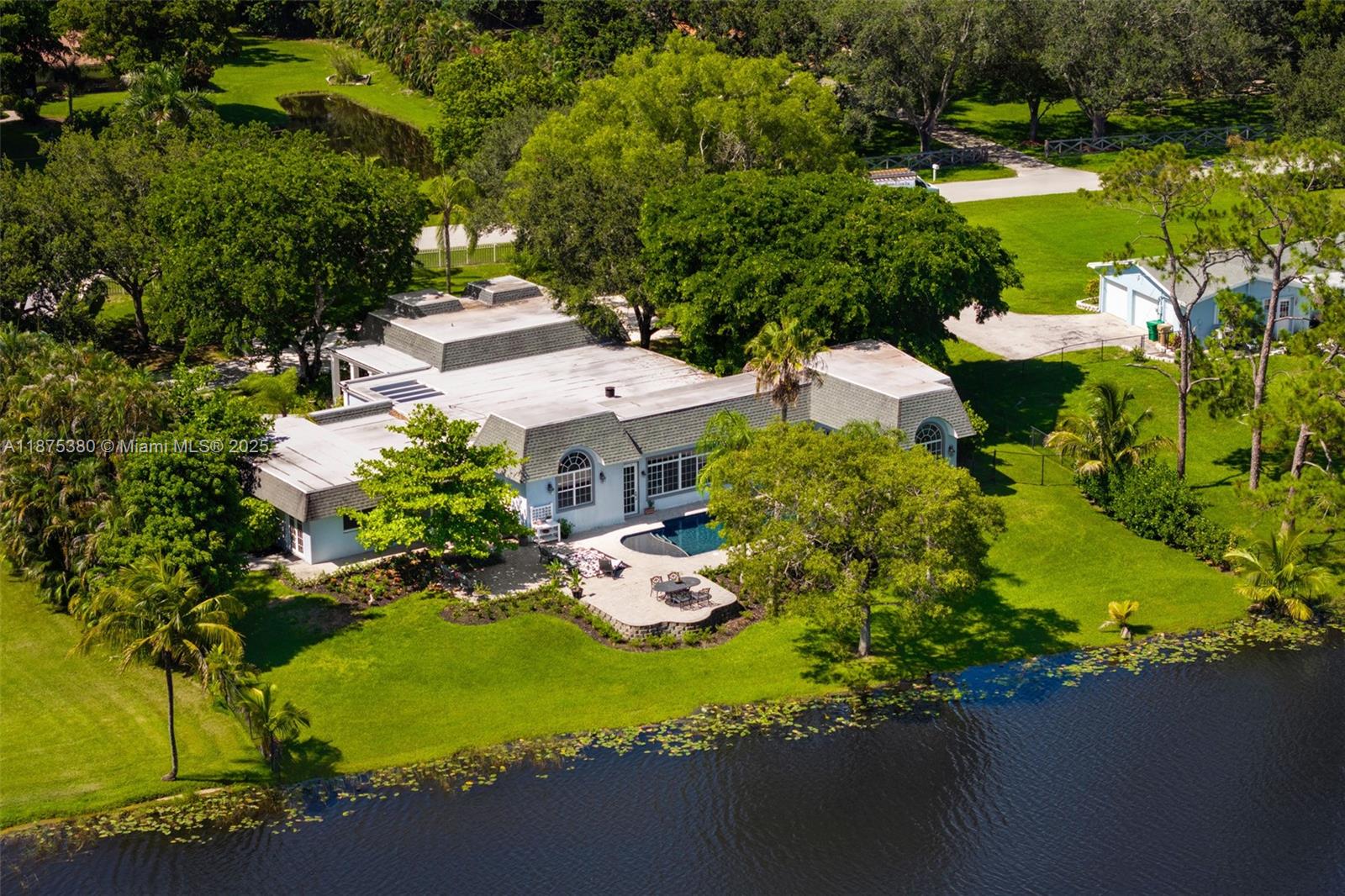 This European-inspired Dutch-style lakefront estate in Davie blends architectural charm with modern design. Front and rear additions completed within 15 years introduced soaring ceilings and expansive living areas. Spanning 5,600 SF, the home features 5 beds, 4 baths, a guest wing, and dedicated office. A dual-island chef’s kitchen anchors the open layout, while the primary suite offers lake views, walk-in closets, and spa bath. Interiors are enhanced with custom finishes throughout. Outdoors, enjoy nearly an acre with a lakefront pool, full sports court, and oversized garage with golf cart parking. One of few custom estates in Davie West, this home offers a rare mix of architectural pedigree, newer construction, and a peaceful setting.