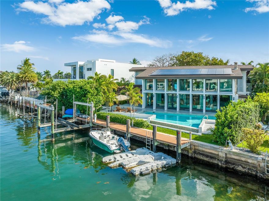 Designed by renowned architect Barry Sugarman, discover your coastal sanctuary where panoramic windows frame breathtaking views of the shimmering pool and the tranquil canal of the sea—perfect for yacht lovers. Natural light floods the space, creating a serene ambiance of peace and tranquility. This elegant home features 4 spacious bedrooms, 3.5 baths, and an elevator connecting the levels. The stunning walnut floors complement the Italian kitchen with a ceiling of warm wood. A Gumbo Limbo tree in the lush garden adds warmth and freshness, while solar panels on the roof ensure energy efficiency. Experience a harmonious blend of luxury, nature, and sophisticated design.