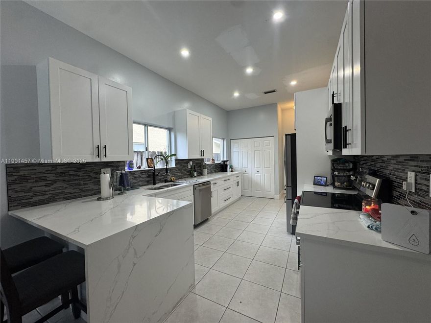 Beautifully updated and well maintained home with volume ceilings, and modern finishes feauturing a custom kitchen with quartz countertops, stainless appliances, and white shaker cabinetry providing plenty of storage. An expansive primary suite boasts a large closet with an updated en-suite bathroom equipped with dual sinks and an oversized walk-in glass shower, while the 3 additional bedrooms are complemented by another stylish bathroom. Private fenced backyard with an inground pool, cabana bath, and fruit trees are perfect for outdoor living with family and friends. This home includes 2-car garage, additional parking, hurricane shutters, and a prime location near A+ schools, parks, shopping, Krome Ave, and future highway access — blending comfort, convenience, and the Florida lifestyle.