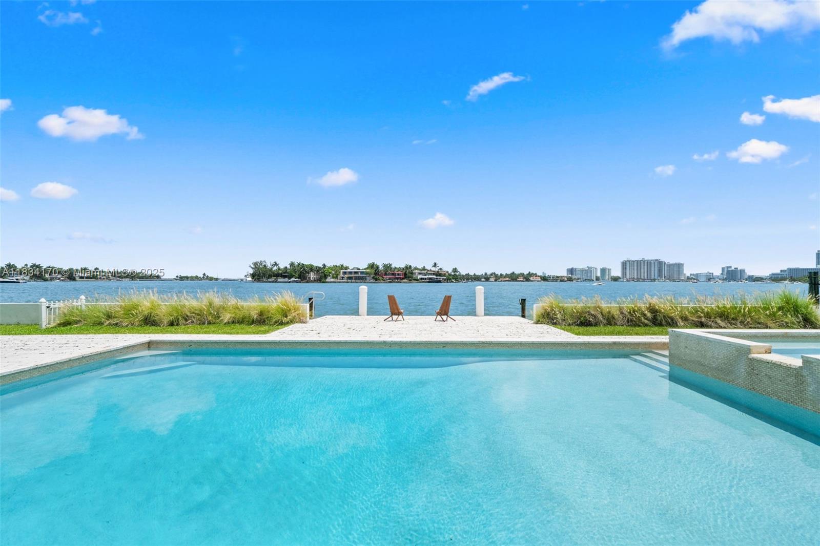 Discover 205 N Hibiscus Drive, a modern waterfront estate on the private, guard-gated Hibiscus Island in Miami Beach. This stunning home features walls of glass with breathtaking bay views and an open floor plan blending indoor and outdoor living. The chef’s kitchen is equipped with premium appliances and custom cabinetry, perfect for entertaining. A separate guest beach house offers privacy and comfort, featuring retractable doors, a lounge, full bath, and outdoor grilling area. Enjoy a spacious terrace, waterfront pool, lush landscaping, and private dock with direct ocean access. Located minutes from South Beach, Downtown Miami, Design District, and Wynwood.