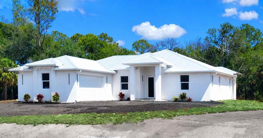 Stunning. Unique. One of a kind. Discover this spectacular new construction in Montura Ranch Estate, Florida. From the very first glance, the beauty of the construction is evident, along with its modern structure, very high ceilings, and metal roof. It is situated on a 1.25-acre lot filled with trees. 3bed and 2 bath.
Inside this new construction, you can appreciate the spacious layout and the use of high-quality materials. The living area is expansive and connects seamlessly with a kitchen equipped with new stainless steel appliances, quartz countertops, and an Oversized U-shaped island that maximizes comfort. Large impact doors and windows allow abundant natural light to enter and offer green views of the trees and surrounding nature, visible from both the living room and kitchen. The entire home is decorated with gold accents, white ceramic floors with gold details, and beautiful light fixtures, especially above the kitchen island.
The primary bathroom features both a shower and a bathtub, with gold details that create a luxurious style, as well as dual sinks. It includes a high-quality ceramic tub, a glass-enclosed shower, and windows overlooking the natural backyard area. The property also includes a washer and dryer, along with all new stainless steel appliances. All bedrooms are equipped with ceiling fans.