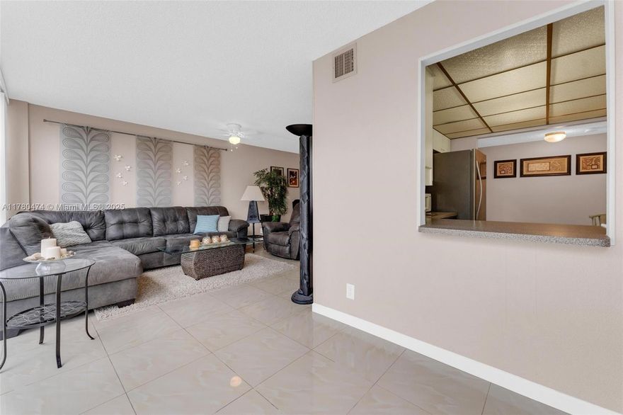 This corner unit features two bedrooms, one full bathroom, and a half bathroom, spanning 1,200 square feet of living space. The floor-to-ceiling windows provide ample natural light, while the tile floors and screened-in balcony add to the modern aesthetic. Cable TV and internet are included in the maintenance fee. Residents can enjoy the heated pool, tennis courts, sauna, and clubhouse/social room. Conveniently located near Joseph Scavo Park, shopping, and Hallandale Beach, this property offers a perfect blend of comfort and convenience.