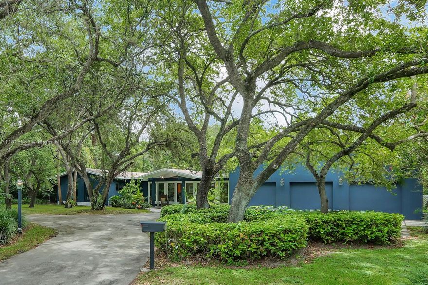 Sprawling 5 bedroom, 4 bath home with charming 1 bed, 1 bath guest house is nestled on an acre of gracious oaks and lush greenery. Meandering pathways lead to quiet spots for relaxation and nature watching. Unique home has oversized windows showcasing serene views. Wood vaulted ceiling accents main living. Expansive primary suite features spacious sitting area with skylights and plantation shutters overlooking lush gardens. Gather with friends in the large entertainment room with mahogany pub-style bar. Home boasts office space, fireplace, and generously sized rooms. Kitchen features Corian counters, sleek Italian cabinetry, and built in Sub Zero. Roof 2021 and impact windows 2020. The 548-sf guest house has laundry and private driveway. A jewel of a home for entertainment and gathering!