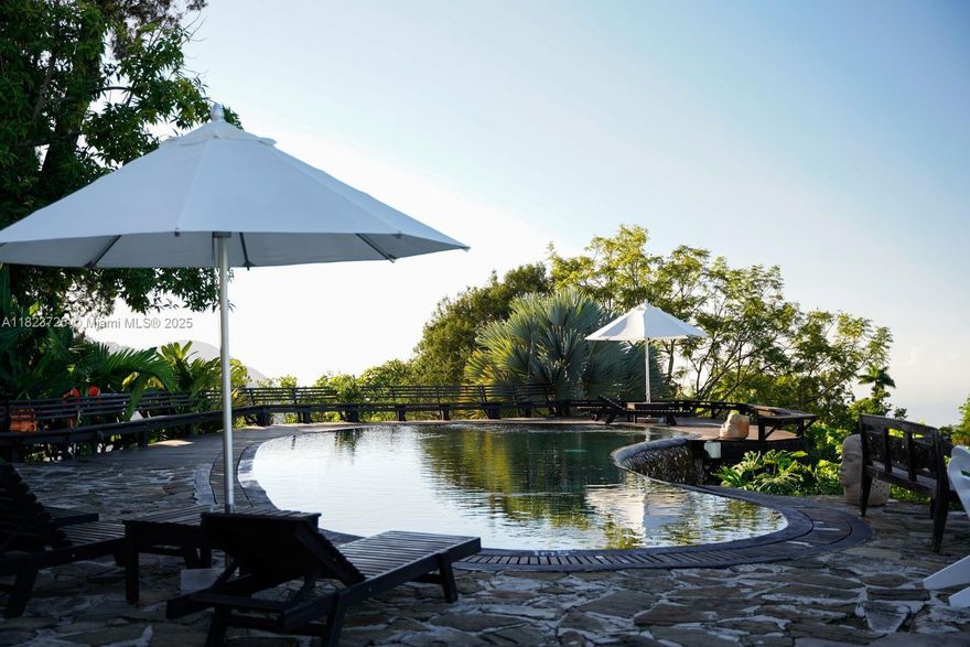 Presenting Strawberry Hill—an iconic mountaintop retreat in Jamaica’s Blue Mountains. Spanning 47.11 acres, this offering includes the renowned boutique hotel, flat development-ready land, and Ropley. The current resort operates on 26 acres with 13 keys and 16 bedrooms, surrounded by lush gardens and panoramic views. Amenities include infinity-edge pool, spa, helipad, gourmet restaurant, bar, library, and event pavilion. Approved plans allow for 16 additional cottages and expanded amenities. A premier investment in one of the Caribbean’s most resilient luxury tourism markets.