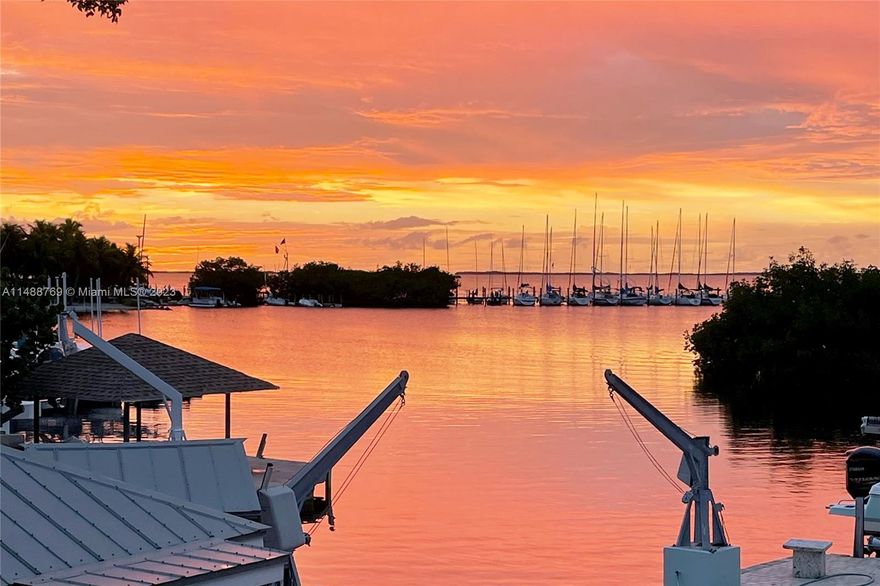 A Sunset Cove nestled on OPEN WATER!  This 3 bedroom 2.5 bath home has a shallow swim basin with ladder, dive board, custom tiki and footbridge that adjoins the 15,000lb lift and 29' dock, davits and  bay bottom. The upstairs offers an open-concept design showcasing the bay from every angle. The master suite includes an en-suite bathroom, walk in closet and opens to an expansive balcony where open water views stretch out endlessly.  The luxury kitchen with expansive island has waterfall quartz countertops and stainess steele appliances, making it a chef's dream and an entertainment delight. The large back balcony is the perfect spot to enjoy the best sunsets or for entertaining. Downstairs has two bedrooms, living area with extra bed, full bath and laundry. FLood insurance is transferable.