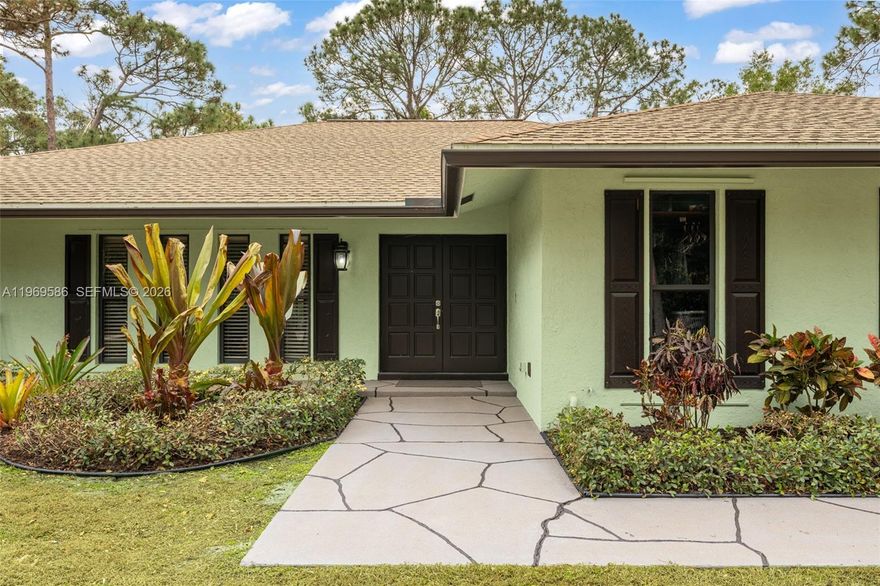 Stunning, fully renovated 2,154 SF one-story CBS home on a high and dry 1.6-acre corner lot in Jupiter Farms. Light-filled 4BR/2BA split floor plan with open-concept living. Designer kitchen features custom white birch cabinetry, premium granite countertops, bar seating, and a pass-through to the patio. Crown molding and waterproof luxury vinyl flooring throughout. Spacious primary suite with oversized walk-in closet and updated bath. An expansive screened porch spans the full width of the home, offering serene acreage views. Oversized 2-car garage. Turnkey, private, and just minutes from Indiantown Rd.