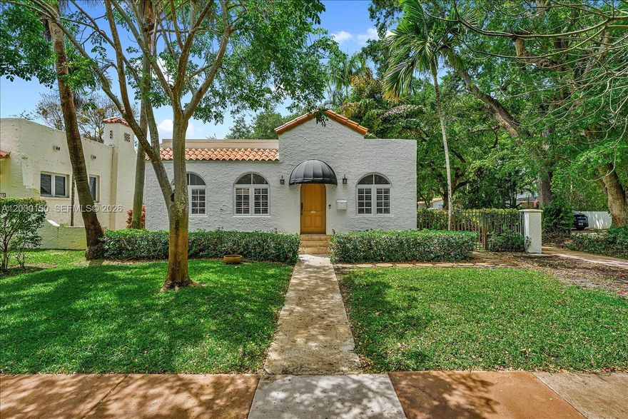 Ideally situated in the historic Granada section of Coral Gables, this charming Old Spanish residence offers a premier location just steps from the scenic Granada Golf Course and minutes from the luxury amenities of the Biltmore Hotel and the upscale dining of Miracle Mile. Featuring 3 bedrooms and 1 bathroom across 1,944 total SF on a 5,250 SF lot, the home is rich in character with crown moldings, graceful arches, arched windows, and plantation shutters throughout. Marble flooring enhances the social areas and kitchen, while warm wood floors bring comfort to the bedrooms. A welcoming living and dining area with fireplace creates an inviting setting for both everyday living and entertaining. The spacious entry foyer provides flexibility for a seating area or additional family space. The well-appointed kitchen includes wood cabinetry, granite countertops, a full suite of appliances, and convenient in-kitchen laundry. The thoughtfully designed layout includes a generous primary suite with a private sitting room, plus two additional bedrooms and a centrally located, renovated bathroom with a frameless glass barn-style shower door. Additional highlights include high-impact windows, distinctive curb appeal with an arched wood entry door and awning, and a durable hybrid roof design. Outdoors, enjoy a private side yard with artificial turf, lush tropical landscaping, privacy hedges, and a paver driveway complemented by a covered one-car carport.