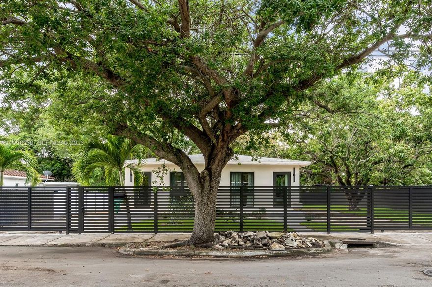 Wabi Sabi retreat on an oversized 7,650 SF corner lot in one of Miami's fastest-moving corridors. Move in now, build up later. Fully renovated single-story residence with vaulted ceilings throughout, 3 bedrooms, 3 full bathrooms finished in hand-applied microcement, and new hurricane-impact windows and sliding doors. Wood floors, central AC, and a 2-car garage. Offered furnished — designer pieces negotiable. Rare corner lot with dual driveways, mature mango, almond, and avocado trees, a designer outdoor shower, and room for a pool. New 6-foot privacy fence and gate. East-facing exposure with a garden setting that feels nothing like the city just minutes away. T4-R zoning on 7,650 SF allows up to a 6-unit, three-story building — or take advantage of Miami's Apartment Hotel designation for short-term rental income. Rental demand in this submarket runs significantly above national averages, so the carry pencils while you permit and plan. Walking distance to the Design District. Minutes from the $3B Little River District, Midtown, Wynwood, and I-95. This is the path of progress — priced to reflect the land value, with a turnkey home providing incredible added value.