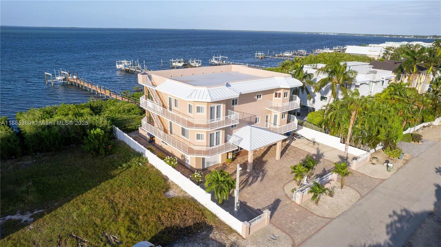 Live the ultimate Florida Keys lifestyle in this luxurious 5-bed, 5-bath estate! Boasting 4,822 sq. ft. of living space and a total building area of 10,791 sq. ft., this masterpiece is designed for comfort and elegance. The bottom floor includes a 1,300 sq. ft. legal enclosure, and an office on the third floor can convert into a sixth bedroom. High ceilings, 8-ft doors, and expansive interiors create an open, airy feel. A private, fenced yard with a heated pool & spa offers a tranquil retreat, enhanced by security cameras, two electric gates, and an intercom. A grand foyer leads to a stunning staircase or an 8-ft elevator. Enjoy breathtaking ocean views from the elegant living & dining area. The chef’s kitchen boasts a Benihana cooking station, top-tier appliances, and ample storage.
