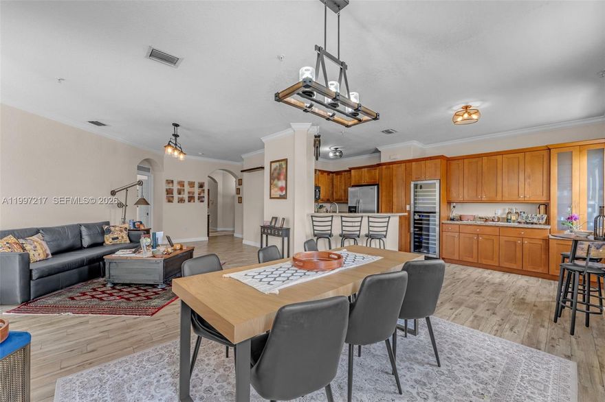 This 3-bedroom, 2.5-bathroom corner unit in the desirable Las Sevillas community offers 1,491 square feet of comfortable living space with an open-concept layout and increased privacy. The home features spacious living and dining areas with lake views, enhanced by elegant wood-look tile. The modern, expanded kitchen showcases sleek finishes, ample cabinetry, and a full-height, built-in wine/beverage fridge. Removing the previous dividing wall created an open flow from the kitchen and dining room into the main living spaces and out to a private balcony. All three bedrooms are generously sized, including a primary suite with a walk-in closet and private bath. A convenient half-bath for guests adds to the home’s functionality. Residents enjoy a gated, well-maintained community with amenities such as a pool, playground, and bike/jog paths, along with two assigned parking spaces and guest parking close to the unit. Ideally located near premier shopping and dining, this move-in ready home offers the perfect blend of comfort, style, and convenience.