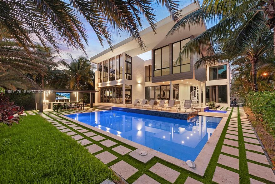 A refined waterfront statement where architecture, light, and scale converge in Golden Isles.

Set within the gated enclave of Golden Isles, this modern residence offers 6 bedrooms, 6 full and 1 half bathrooms across 5,560 SF of interior living on a 12,750 SF lot with 85 feet of canal frontage and direct ocean access with no fixed bridges. Built in 2019, the home delivers a seamless blend of volume and contemporary design, anchored by soaring double-height ceilings and expansive walls of glass that frame the water beyond.

Interiors are thoughtfully composed with open-concept living and dining spaces designed for both everyday comfort and elevated entertaining. A private elevator connects both levels, while custom built-ins, walk-in closets, and refined finishes enhance functionality. The primary suite offers dual custom closets and a spa-inspired bath with a sense of scale and calm.

Outdoor living unfolds as a true extension of the home, where fully retractable glass doors open to a resort-style setting. A heated pool and spa, expansive terrace, and covered entertaining areas are complemented by a summer kitchen. Along the canal, a private dock and boat lift provide effortless access to open ocean while offering privacy and a protected environment for boating.

A rare offering defined by clean lines, indoor-outdoor flow, and a prime waterfront position within one of South Florida’s most established gated communities.