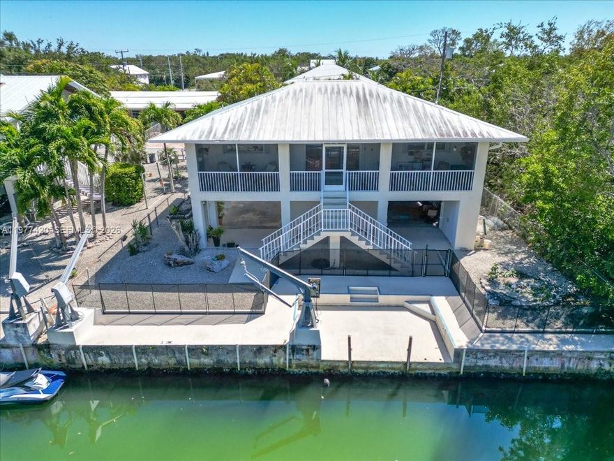 Enjoy Florida Keys waterfront living in the heart of Big Pine Key. This canal-front home with a full concrete seawall and direct boating access offers the perfect opportunity to experience the relaxed Lower Keys lifestyle surrounded by world-class fishing, diving, and boating. The elevated main home features a 2 bedroom, 2 bathroom layout with an open living area, spacious kitchen with built-in cabinetry extending into the dining area, and pocket sliding doors leading to a screened porch overlooking the canal—an ideal spot to enjoy the island breeze. Downstairs is a pre-FIRM finished enclosure with approximately 480 sq ft including an additional 1 bedroom and 1 bathroom, providing flexible space for guests, hobbies, or storage. The fenced lot, drive-through garage, and large utility/laundry area offer plenty of room for boating gear and outdoor equipment.  A rare feature is the added privacy with no neighbors on one side, as the county owns the two adjacent lots which will remain undeveloped. Located in the desirable Eden Pines neighborhood, just minutes from the community boat ramp, local restaurants, and shopping, and approximately 30 minutes to Key West. Close to Bahia Honda State Park, the National Key Deer Refuge, and world-class snorkeling and diving at Looe Key Reef.
