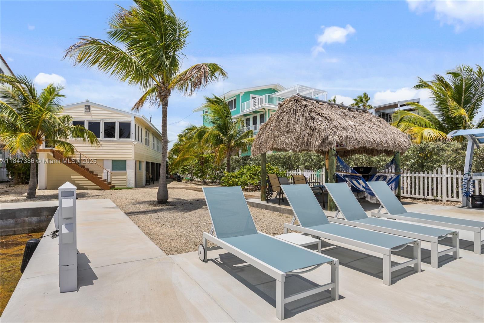 Florida Keys Oceanfront "Fisherman’s Paradise" with breathtaking Atlantic Views and Private Dockage. This fully renovated 3BR/2BA home features an open layout, Dade County Pine woodwork, and floor-to-ceiling impact windows that frame endless ocean vistas. The lower level includes a workshop with full bath and laundry—perfect for guests or gear. Boaters and anglers will love the 50’ seawall, 30’ inlet slip, dock for a 35’ vessel, and a premium fish cleaning station with water and electric. Unwind under the waterfront tiki hut with BBQ, hammock, and seating—ideal for sunrises, sea breezes, and soaking up the Salt Life. Tastefully furnished with coastal charm. Close to shops, dining, and hospital.